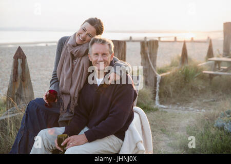 Portrait affectionate mature couple drinking wine on sunset beach Stock Photo