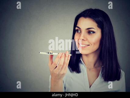 Girl using a smart phone voice recognition function on line isolated on gray wall background Stock Photo