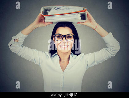 Happy businesswoman with office binders standing grinning at the camera balancing them on her head Stock Photo