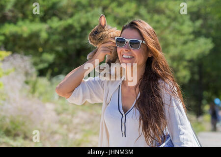 A brunette woman with a rabbit on a walk. Stock Photo