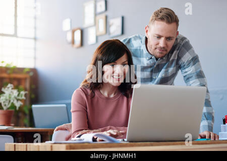 Smiling coworkers using a laptop together in an office Stock Photo