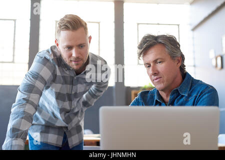 Focused young businessmen using a laptop at an office desk Stock Photo