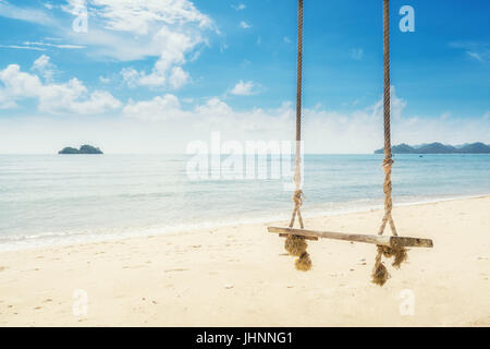 Wooden swing chair hanging on tree near beach at island in Phuket, Thailand. Summer Vacation Travel and Holiday concept. Stock Photo