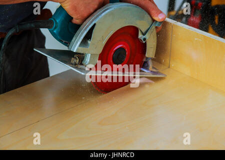 carpenter uses a circular saw to cut wood on the work area Circular saw cutting wooden Stock Photo