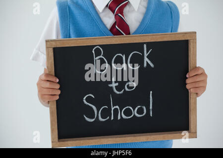 Mid section of schoolboy holding writing slate with text back to school against white background Stock Photo