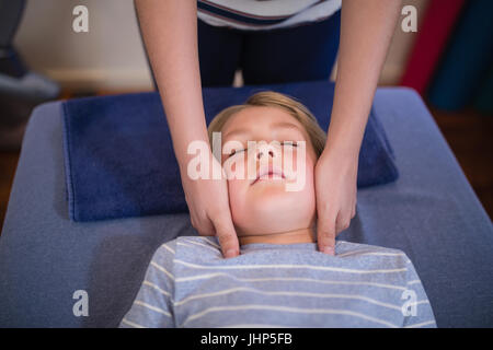 High angle view of boy receiving neck massage from female therapist at hospital ward Stock Photo