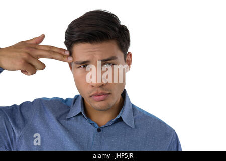 Portrait of businessman with suicide gesture against white background Stock Photo
