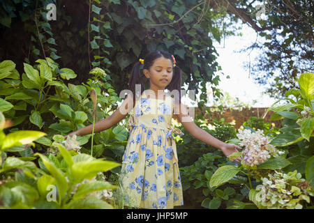 Girl standing amidst green plants in garden Stock Photo