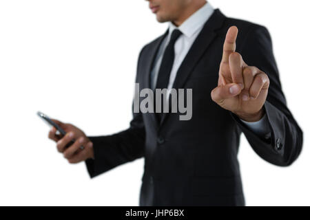 Mid section of businessman using phone while touching invisible interface against white background Stock Photo