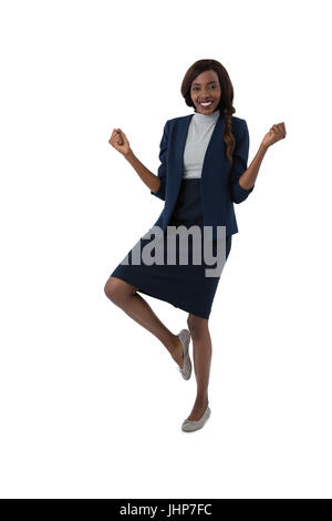 Portrait of happy businesswoman standing on one leg against white background Stock Photo