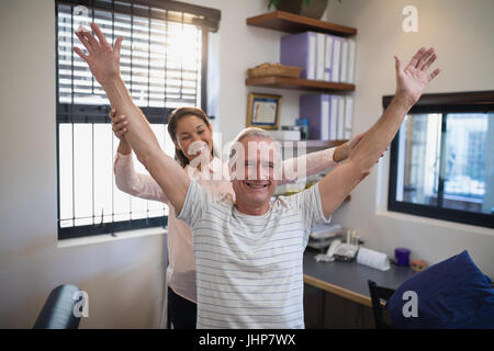 Smiling female doctor and male patient with arms raised at hospital ward Stock Photo