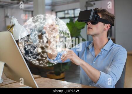 Digital composite of Man in VR headset touching a 3D sphere interface Stock Photo