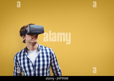 Digital composite of Man in VR headset looking up against yellow background Stock Photo