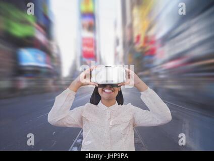 Digital composite of Happy woman in VR headset looking against city background Stock Photo