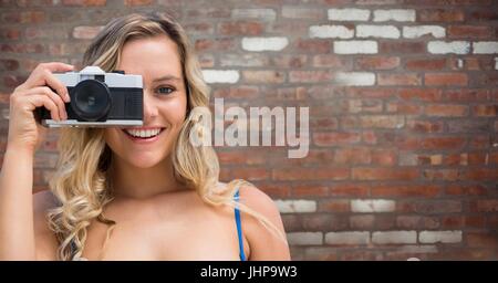 Digital composite of Close up of millennial woman with camera against red brick wall Stock Photo
