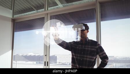 Digital composite of Man in VR headset touching interface Stock Photo