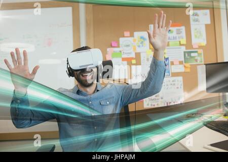 Digital composite of Happy man in VR headset looking to green lights interfaces Stock Photo
