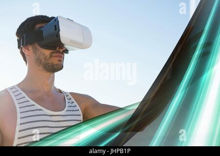 Digital composite of Man in VR headset touching green light interface Stock Photo