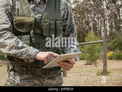 Digital composite of Soldier man using a tablet against field Stock Photo