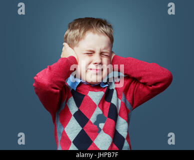 unhappy boy closing ears, isolated against grey Stock Photo