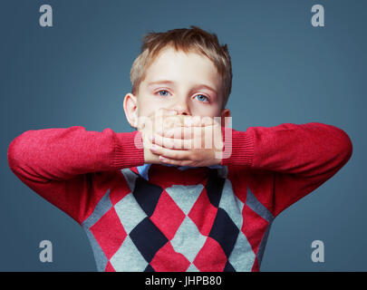 scared boy closign his mouth, isolated against grey Stock Photo