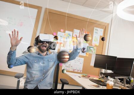 Digital composite of Excited man in VR headset looking at 3D planets Stock Photo