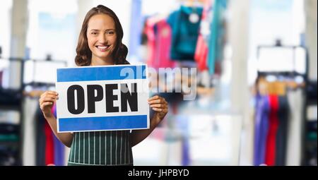 Digital composite of Shop owner with open sign against blurry clothes Stock Photo