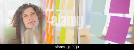 Digital composite of Woman looking up at sticky notes and sticky note transition Stock Photo