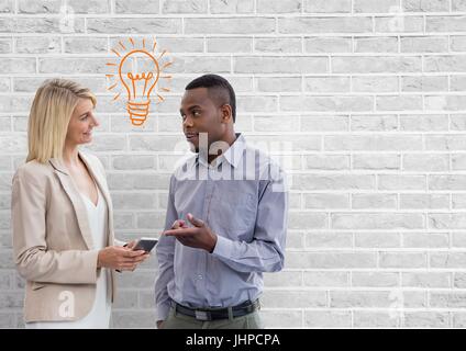 Digital composite of Happy business people talking against white wall with bulb graphic Stock Photo