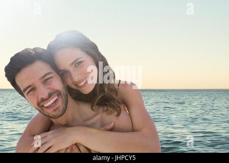 Digital composite of Happy couple at the beach embracing Stock Photo
