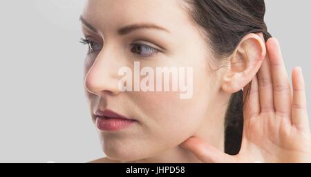 Digital composite of Portrait of woman listening with ear with grey background Stock Photo