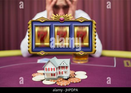 Digital composite of Casino slots spinning with worried man gambling his house in the background Stock Photo