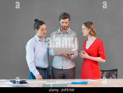Digital composite of Business people at a desk looking at a tablet against grey background Stock Photo