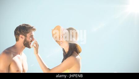 Digital composite of Millennial couple against light blue background with flare Stock Photo