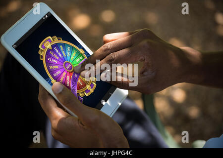 Colorful wheel of fortune on mobile display against man using tablet computer Stock Photo