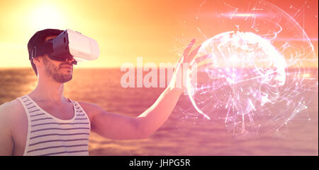 Young man using virtual reality glasses against global technology background in purple Stock Photo
