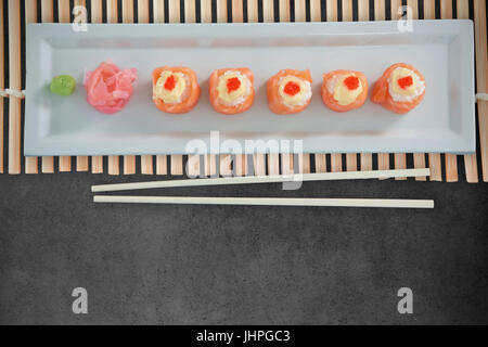 Close up of japanese food arranged in row on plate against close-up of blackboard Stock Photo