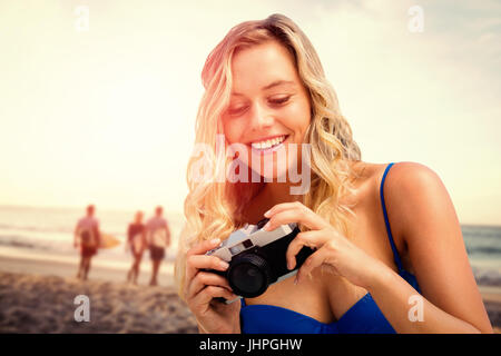 Smiling girl looking her camera against happy friends walking with surfboards