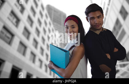 Students posing with crossed arms back against back against low angle view of office towers Stock Photo