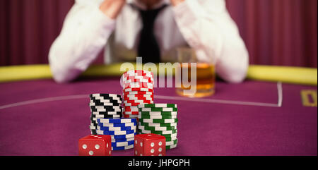Dice with stack of colorful casino tokens against man betting his house at poker game Stock Photo