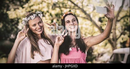 Happy female friends clicking selfie through mobile phone in park Stock Photo