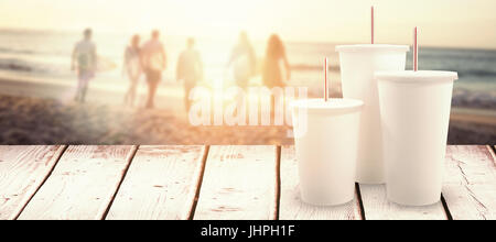 White cups over white background against happy friends walking with surfboards