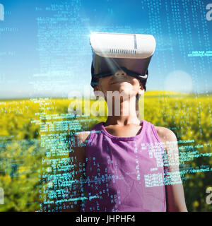 Boy wearing virtual reality glasses against yellow mustard field Stock Photo