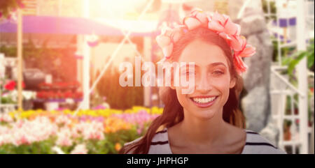 Beautiful smiling woman with a flower crown against fake waterfall in garden center Stock Photo