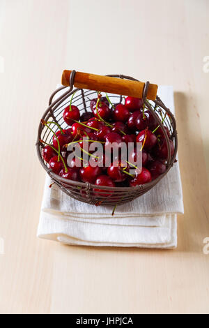 Fresh ripe cherries in an iron basket on a kitchen table Stock Photo