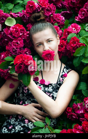 A portrait of a young woman near rose bush Stock Photo