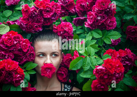 A portrait of a young woman near rose bush Stock Photo