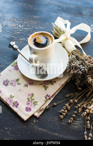 Cup of coffee and dried lavender flowers on dark wooden table Stock Photo