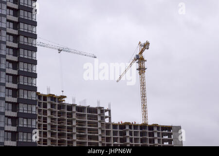 Working tall cranes inside place for with tall buildings under construction Stock Photo