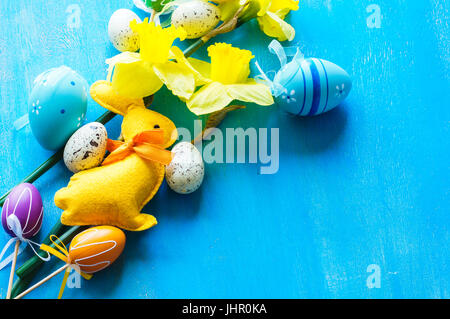 Festive easter frame with yellow daffodils and easter eggs on bright blue wooden background Stock Photo
